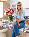 Cathy sitting on a kitchen counter with a vase of flowers