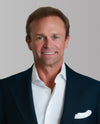 Conner wearing a dark suit and white shirt with a gray background