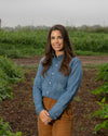 Kristen standing in a field wearing a blue shirt and brown pants.